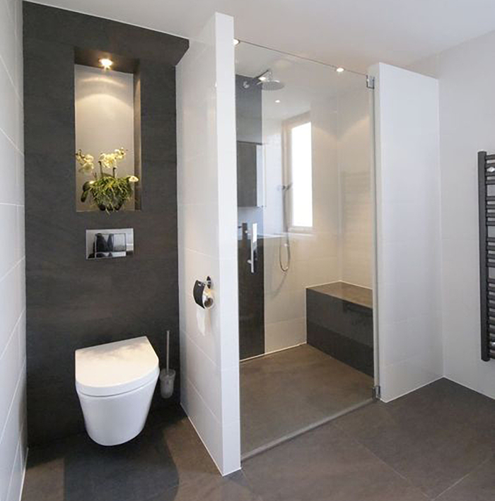 image_manager__BTM1_teilumbau_bad Ein modernes Badezimmer mit weißer Badewanne, grauen Fliesen und einer gläsernen Duschkabine.