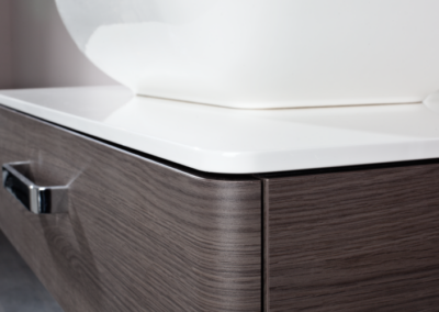 Ein modernes, minimalistisches Möbelstück in Grau und Holzoptik mit klaren Linien und Stauraum.