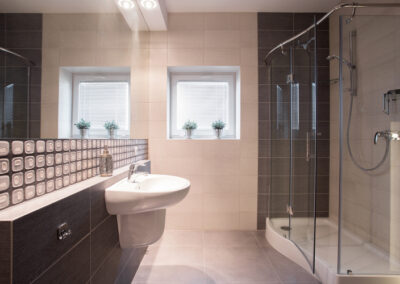 Ein modernes Badezimmer mit einer großen Duschkabine, weißen Fliesen und einer gläsernen Duschwand.