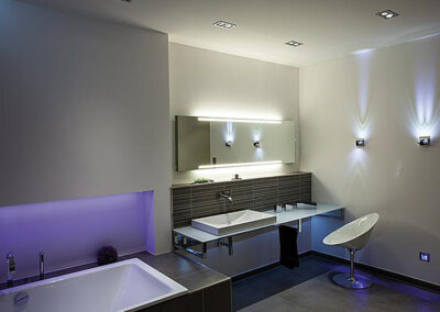 Ein modernes Badezimmer mit indirekter Beleuchtung und Spiegelungseffekten an den Wänden.