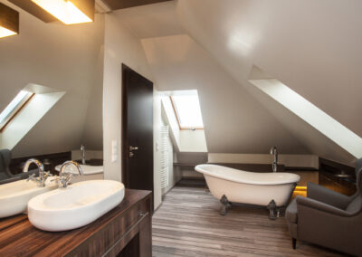 Ein Retro-Badezimmer mit rosa Fliesen, einer Badewanne, einem Spiegel und einer Pflanze.